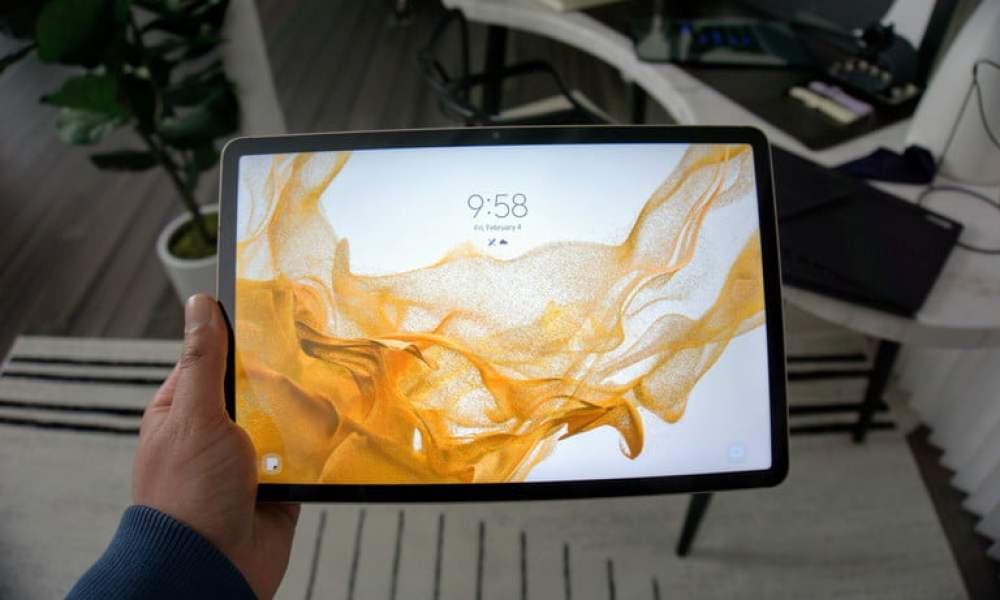 The Samsung Galaxy Tab S8 being held up with the lock screen showing.