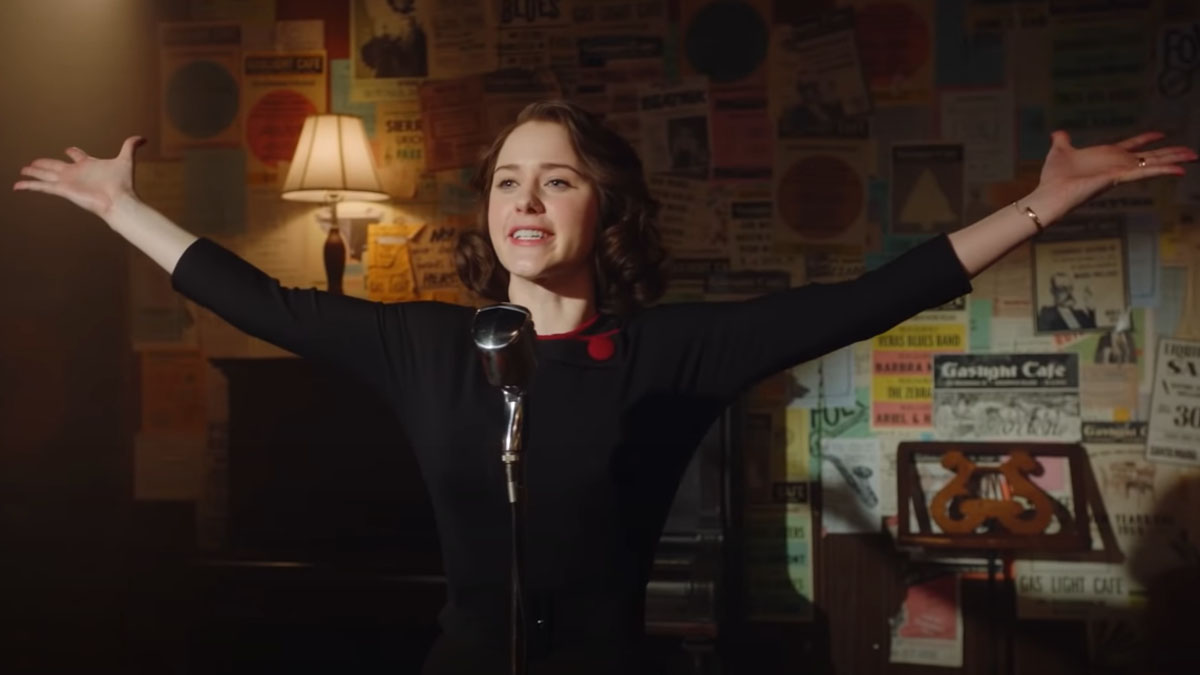 Rachel Brosnahan abre os braços no palco em The Marvelous Mrs. Maise.