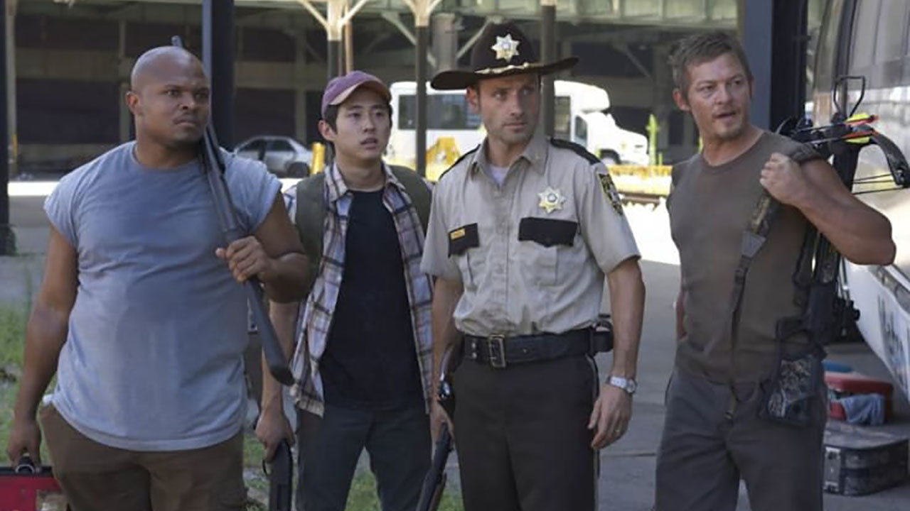 T-Dog, Glenn, Rick, and Daryl standing together in a scene from the first season of The Walking Dead.