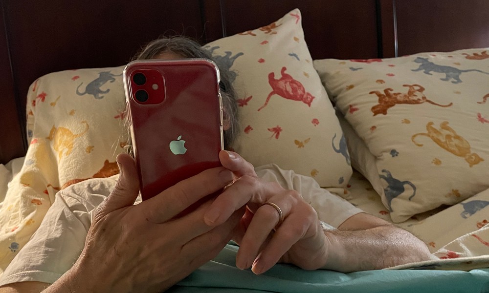 Man lying in bed reading his iPhone.