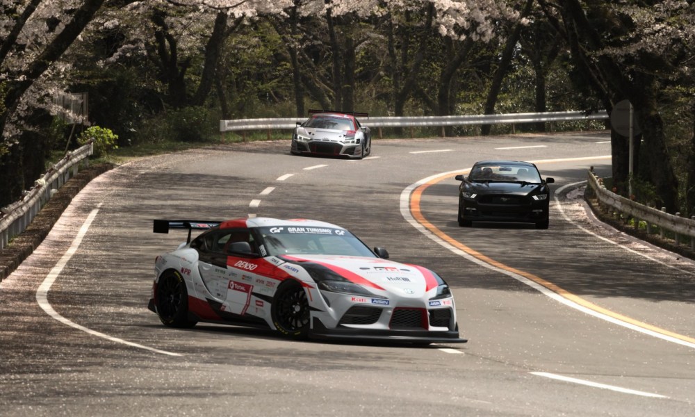 Three cars come racing around a tight turn in Gran Turismo 7.