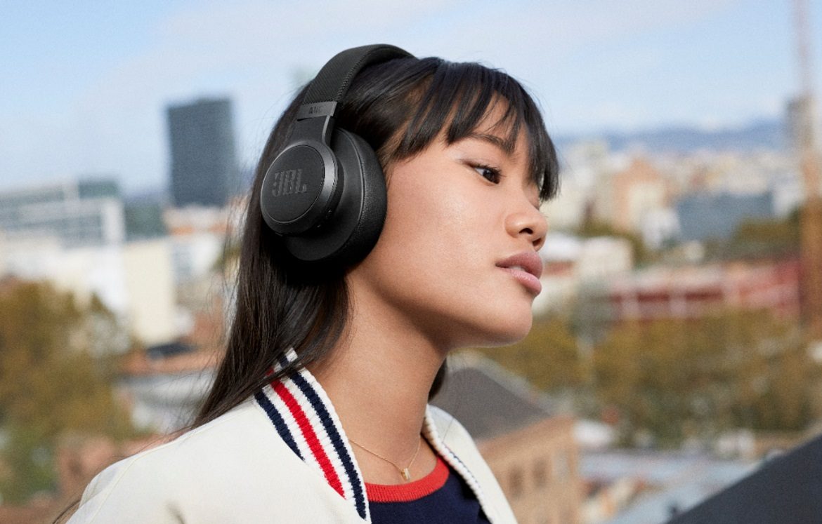 Una mujer que usa los auriculares inalámbricos JBL Live 660NC mientras está al aire libre.