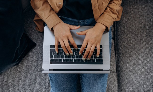 Close up of a person's hands as they type on a laptop's keyboard.