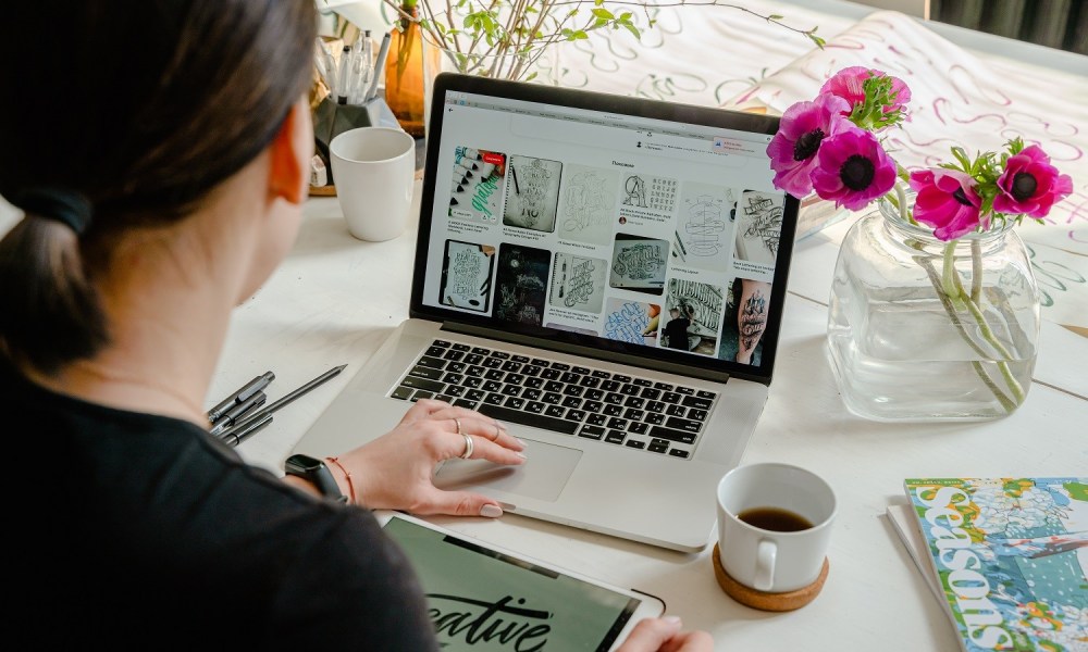 A person using a laptop at a table with flowers.