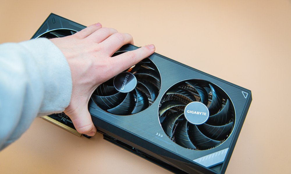 A hand grabbing a graphics card.