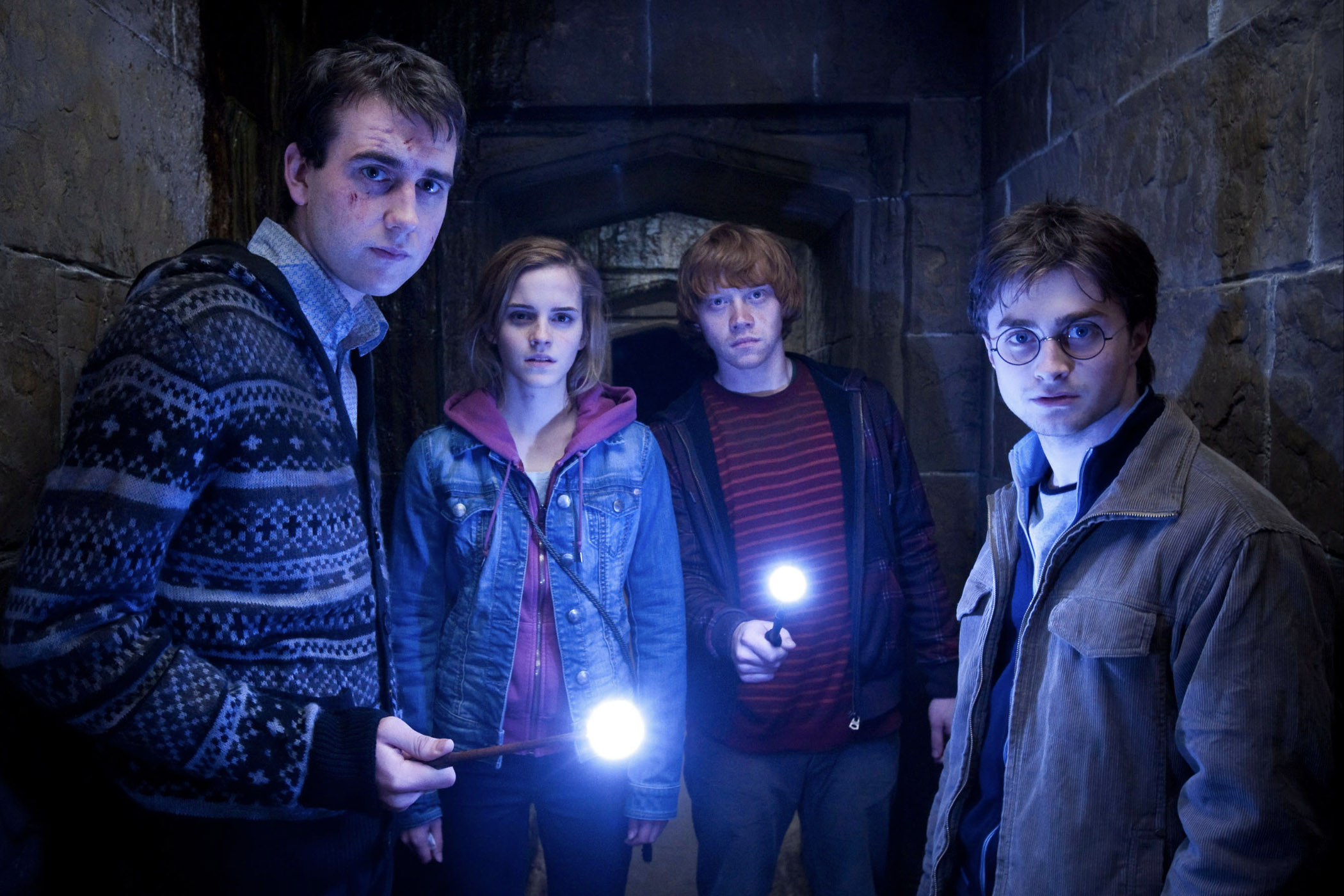 Neville, Hermione, Ron e Harry dentro de um túnel escuro em HP e as Relíquias da Morte Parte 2.