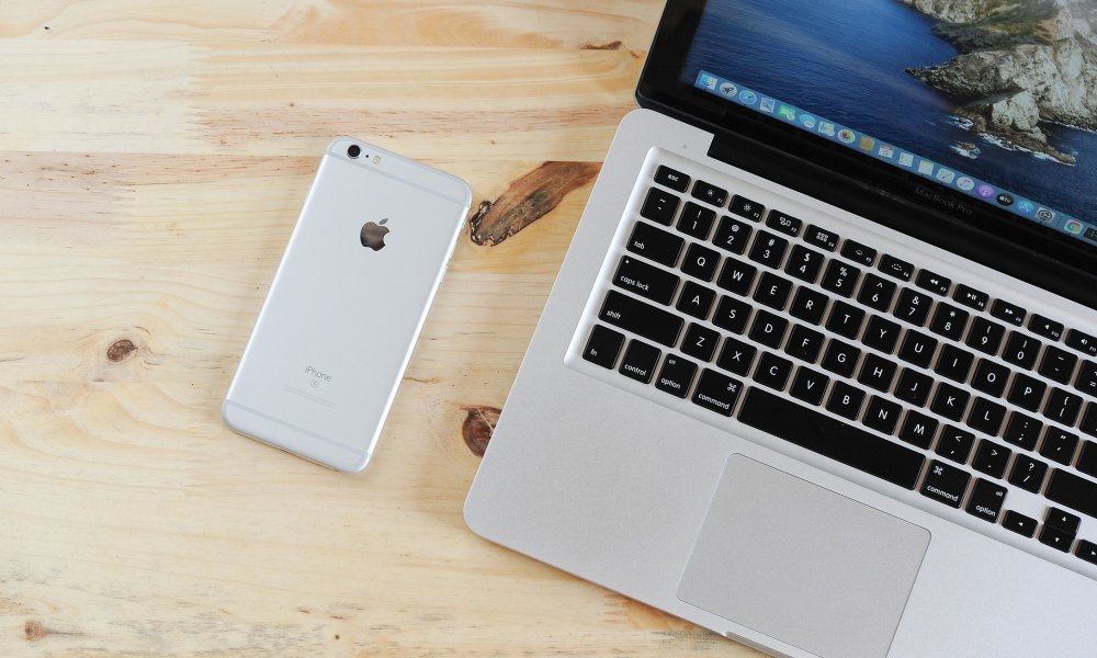 iPhone and a MacBook on a desk.