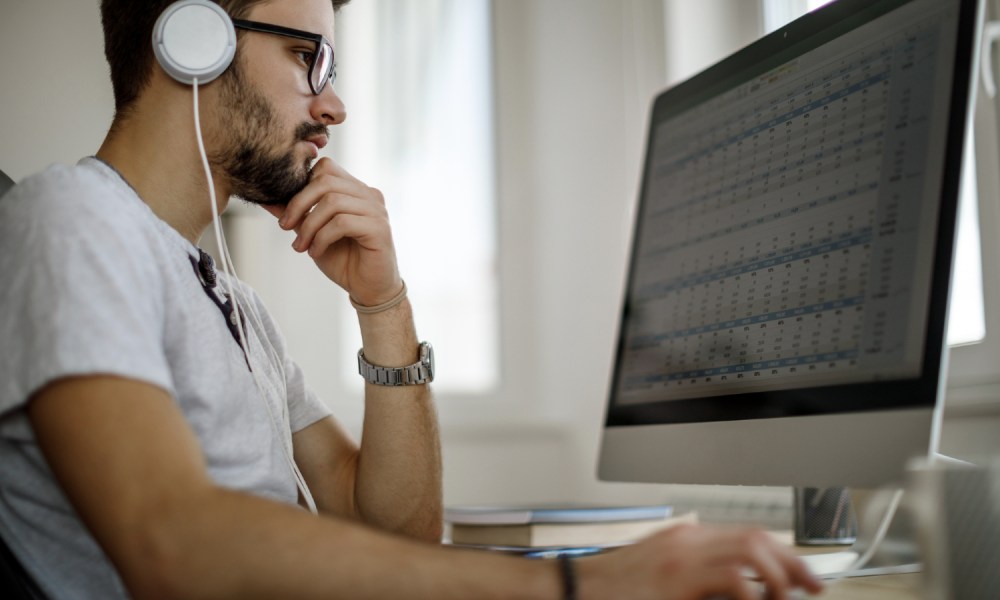 A man using a PC to view an Excel spreadsheet.