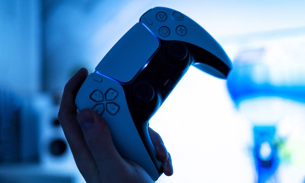 A person holds up a PS5 controller.