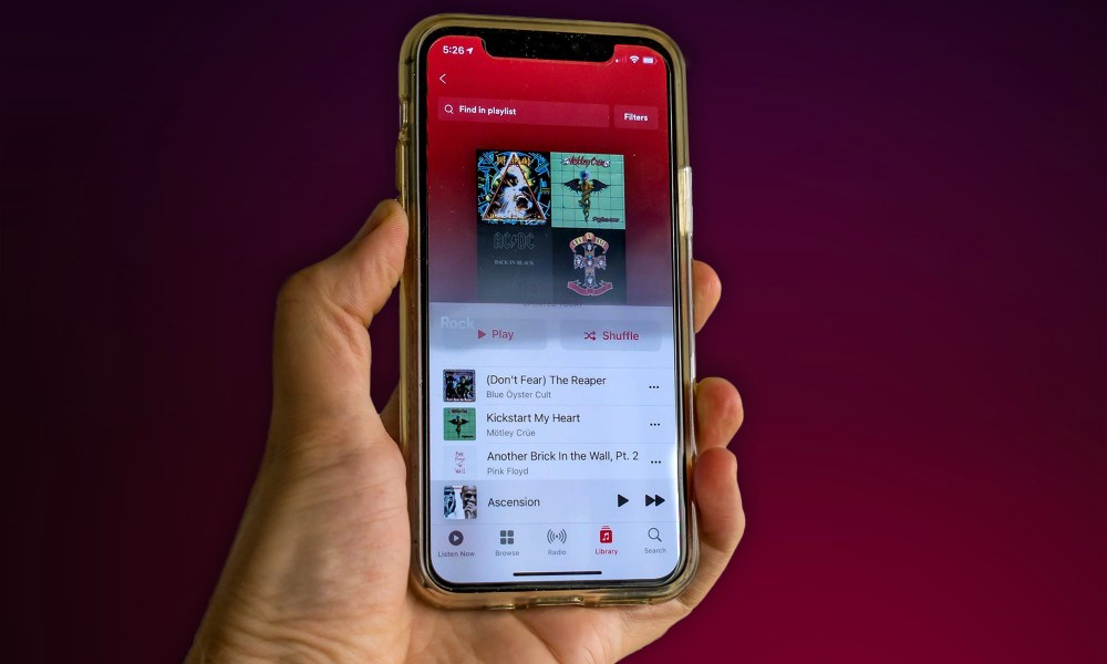 A person holds an iPhone 11 with the Apple Music app open.