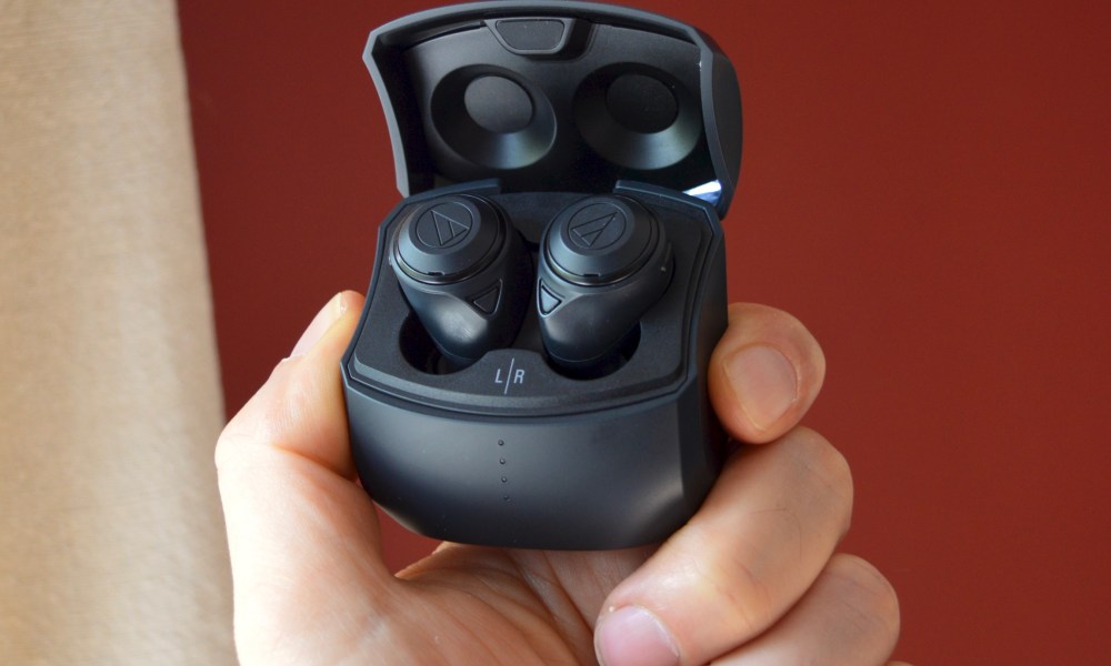 Hand holding Audio-Technica ATH-CKS50TW wireless earbuds in their case.