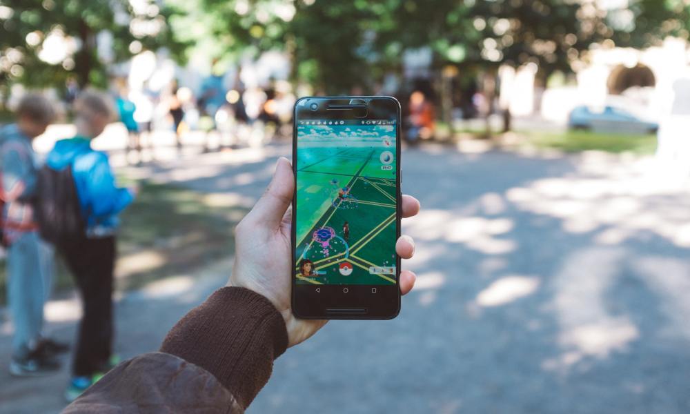 A hand holding a phone with Pokemon Go open.