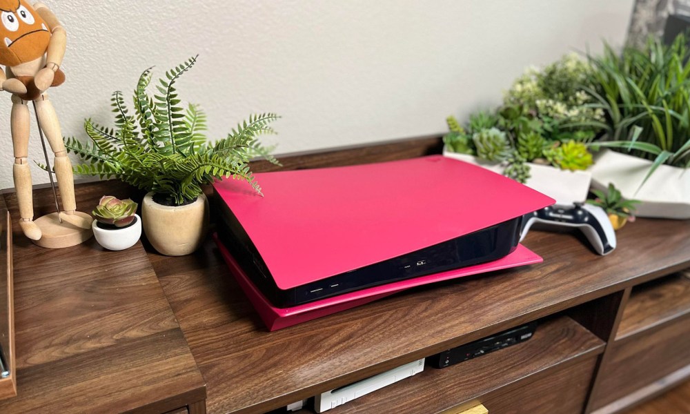 A PS5 sitting in a wood toned entertainment center, showing off it's new red cover.