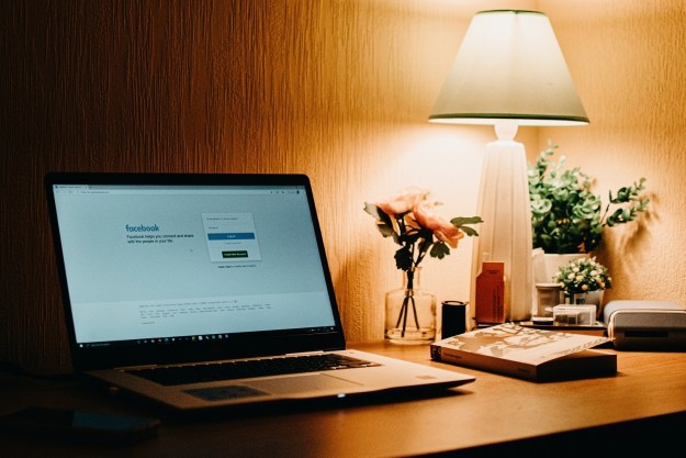 A laptop on a desk with Facebook's website on its screen.