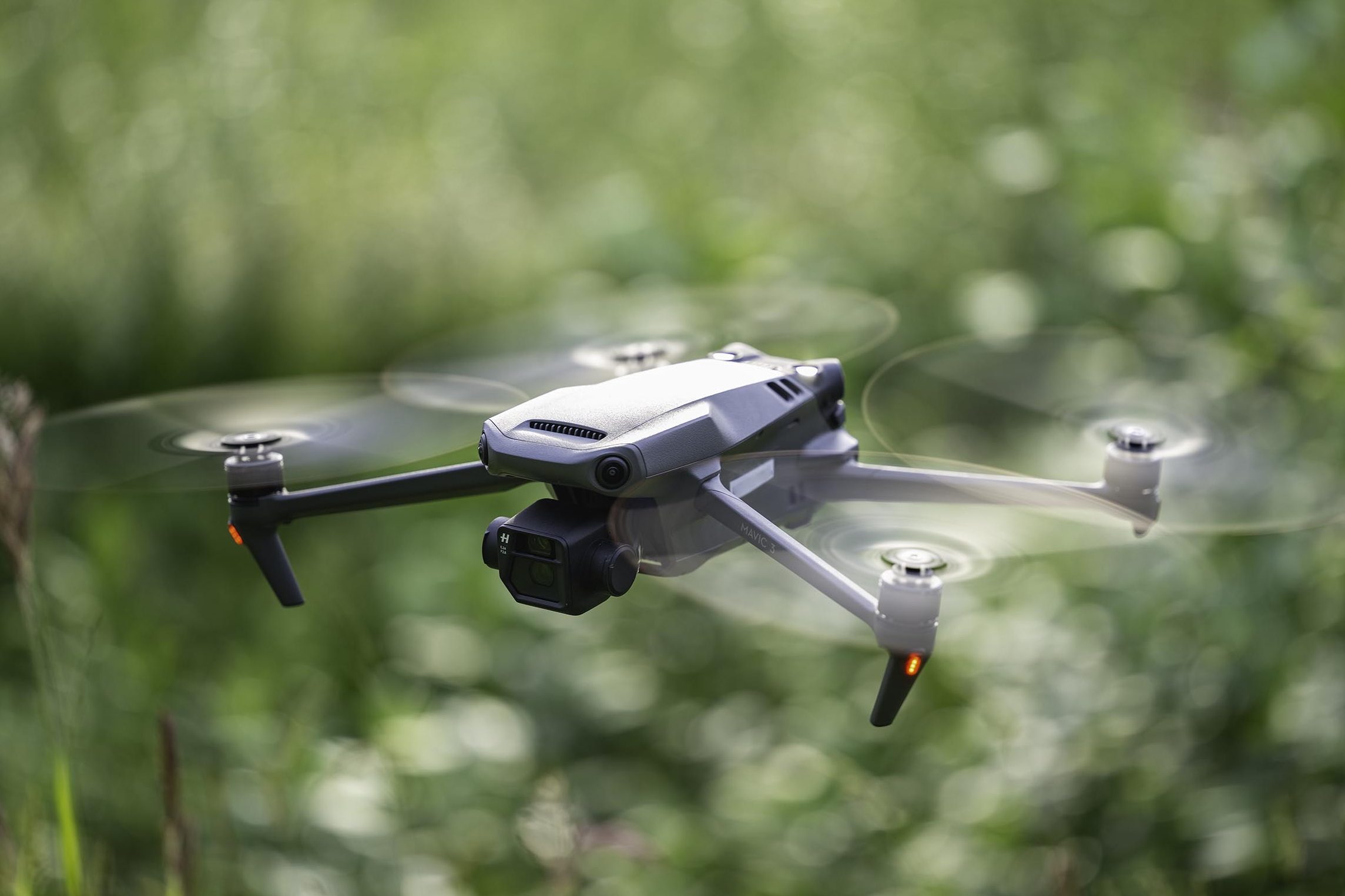 The DJI Mavic 3 in flight with a blurred green background.