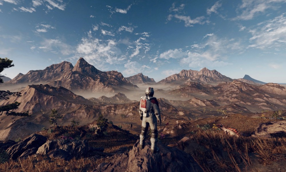 A space explorer stands in front of a mountain range in Starfield.