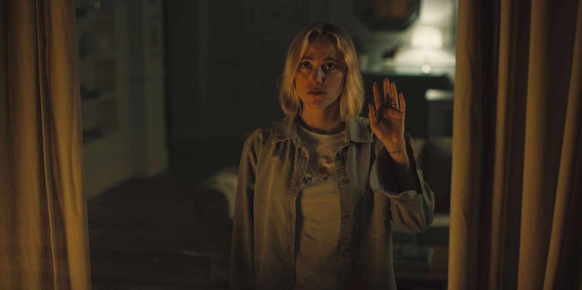 Maika Monroe acena pela janela em Watcher.