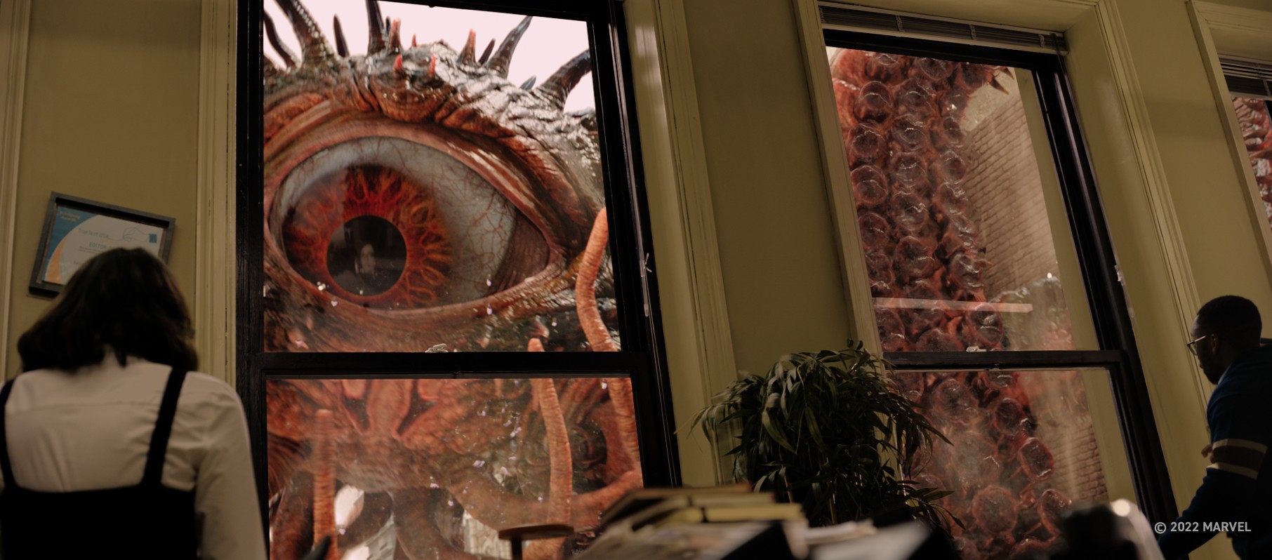 La gente mira por la ventana de un edificio de oficinas con un ojo gigante y tentáculos afuera en una escena de Doctor Strange in the Multiverse of Madness.