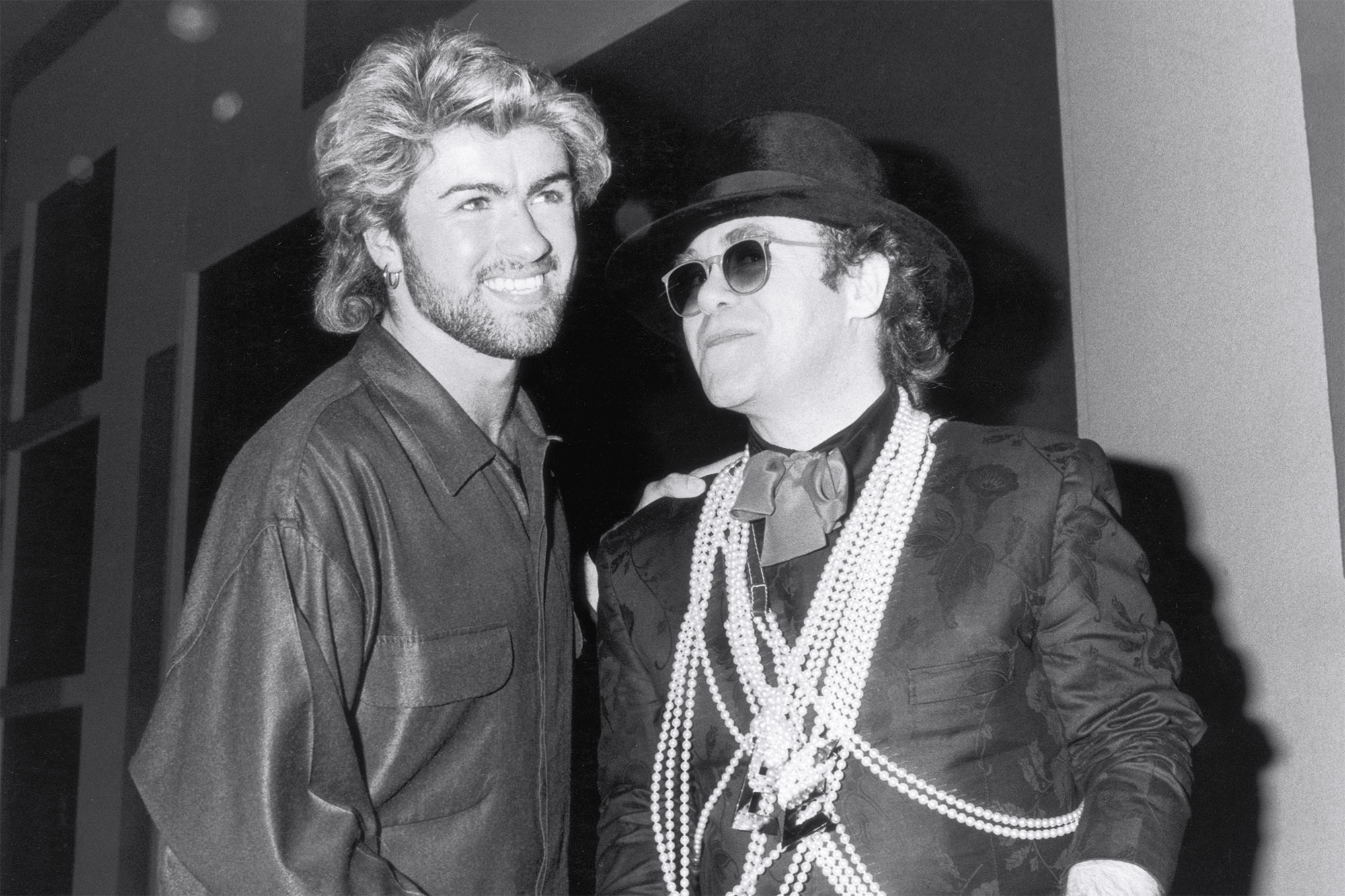 La pop star Elton John (à droite) félicite George Michael d'avoir remporté le prix Ivor Novello de l'auteur-compositeur de l'année au Grosvenor House Hotel de Londres, le 13 mars 1985.