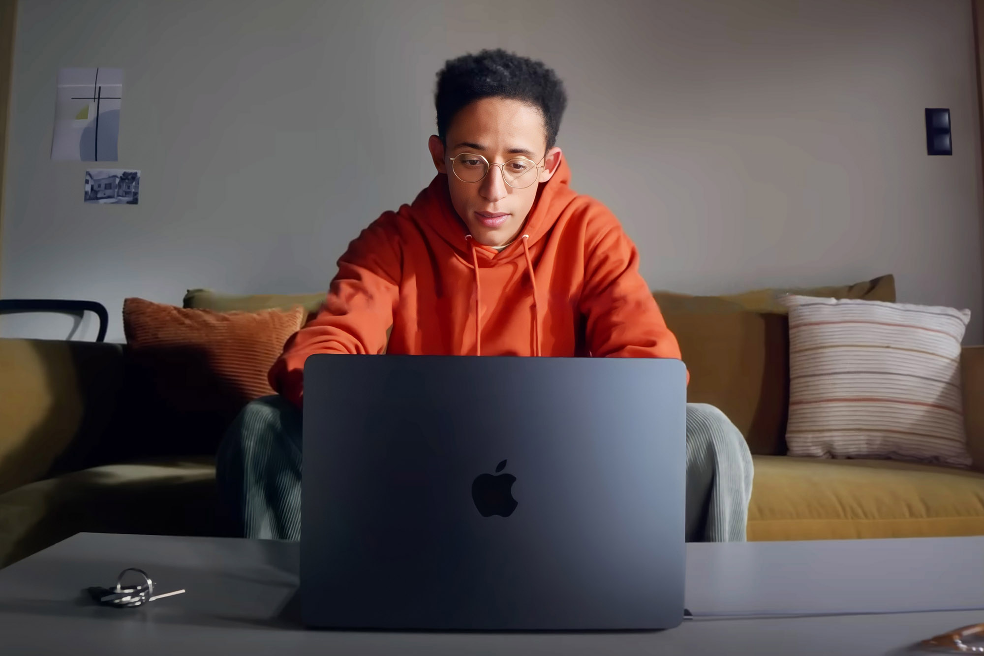 A man sits at his couch using the M2 Macbook Air.