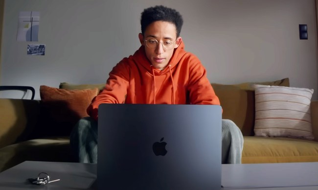 A man sits at his couch using the M2 Macbook Air.