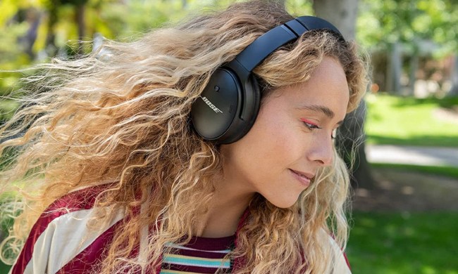 A woman in a park wearing Bose QuietComfort 45 Bluetooth wireless noise canceling headphones.