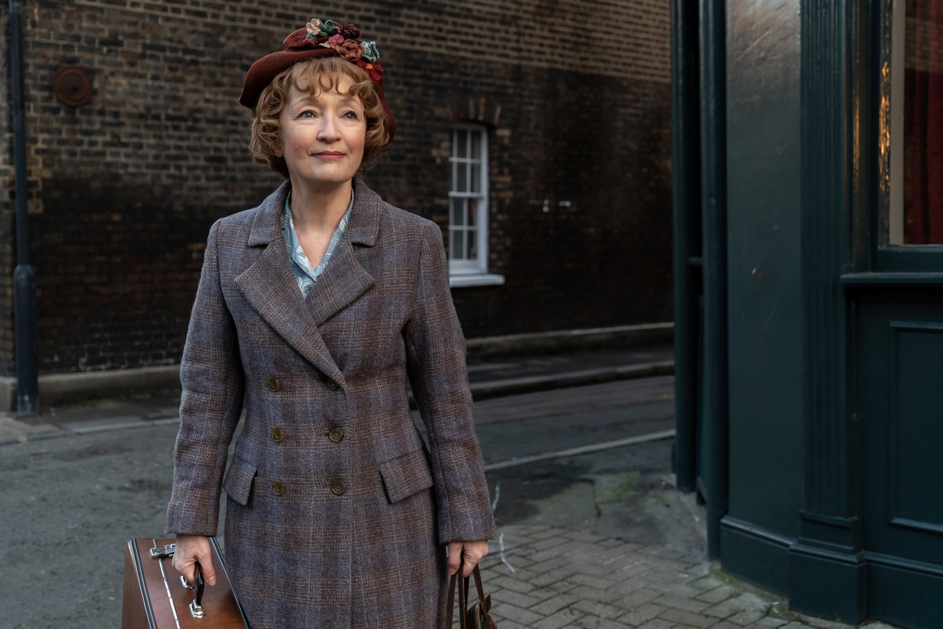 Una mujer se para en la esquina de una calle en Mrs. Harris Goes to Paris.