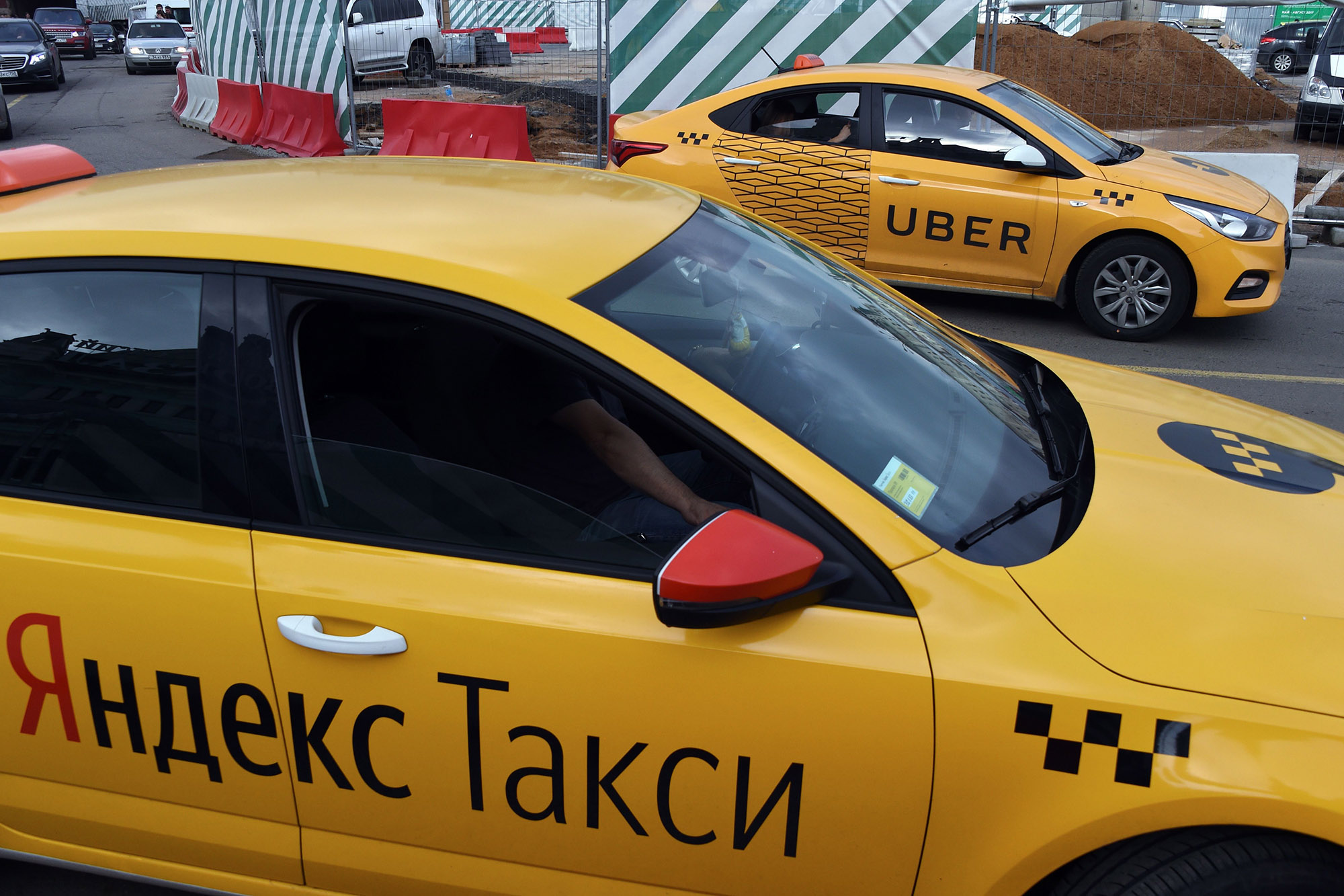 Um carro Uber (atrás) e um carro Yandex.Taxi em uma rua em Moscou.