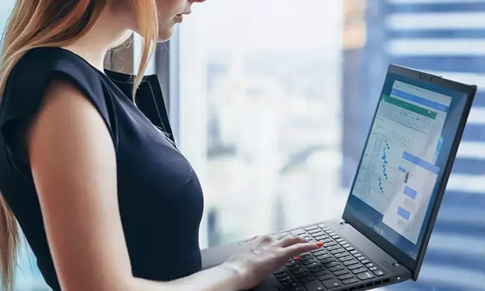 A person holding a ThinkPad Nano X1 Gen 2 laptop in front of a window.