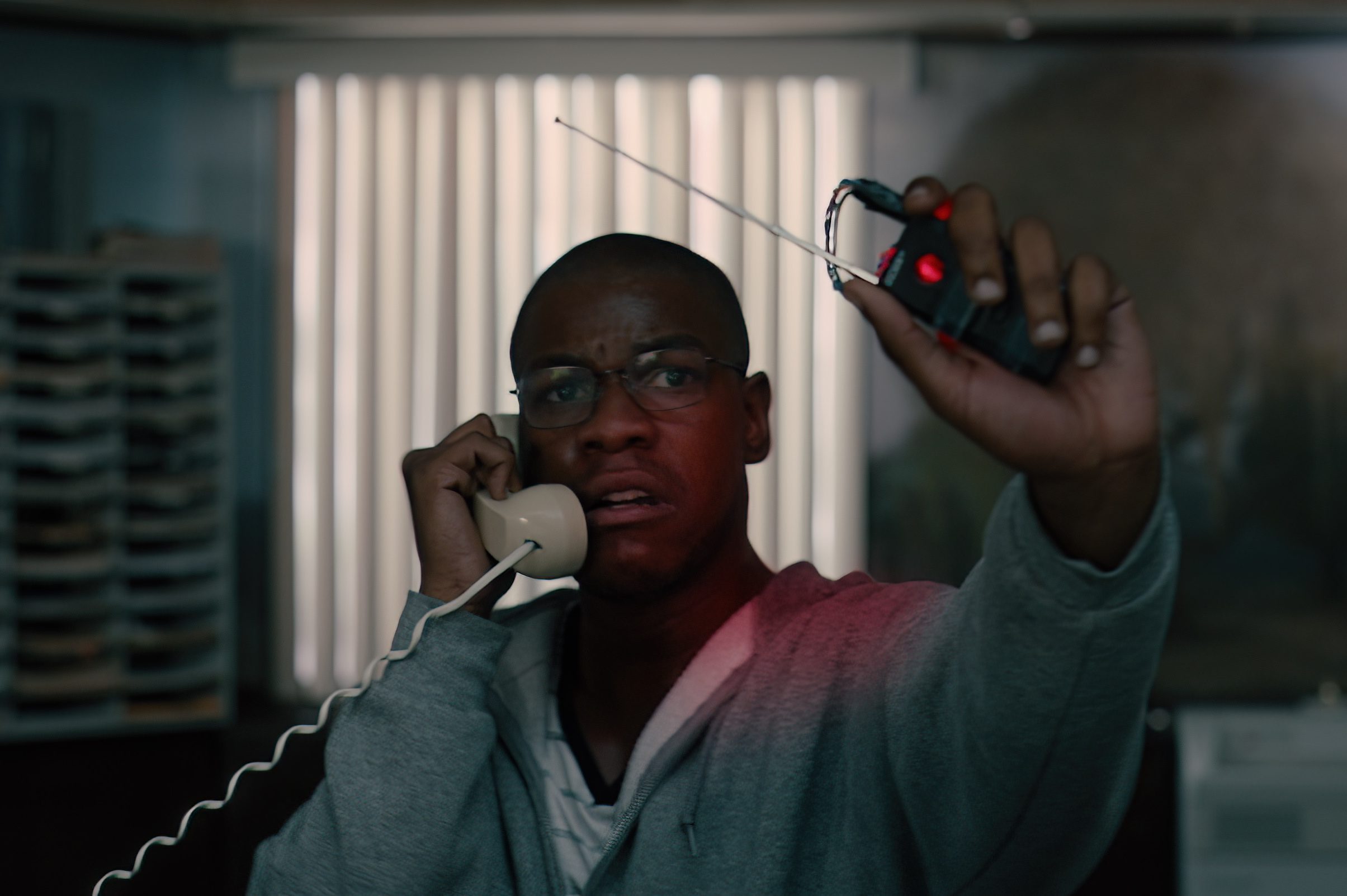 John Boyega segura um gatilho e um telefone em uma cena de Breaking.