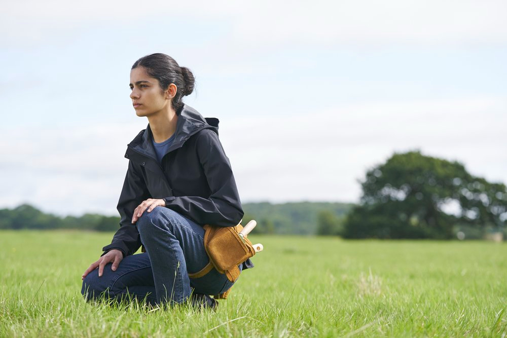 Hannah Khalique-Brown s'agenouille dans un champ d'herbe dans La guerre non déclarée.