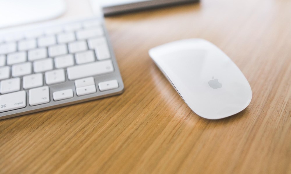 Magic Mouse next to a Mac keyboard on a desk.