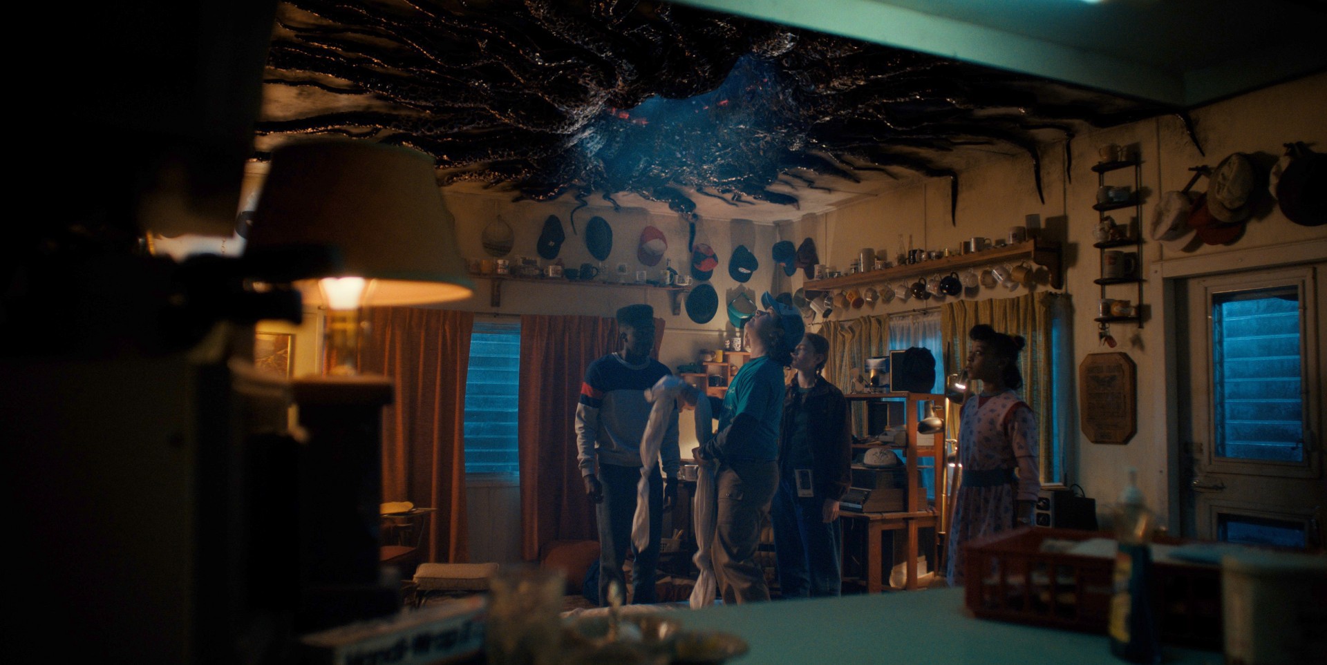 The characters in Stranger Things looks up at a portal in the ceiling of a room.