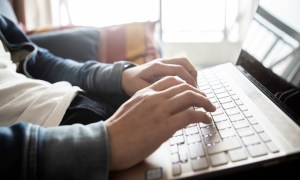 An individual using a laptop's keyboard.