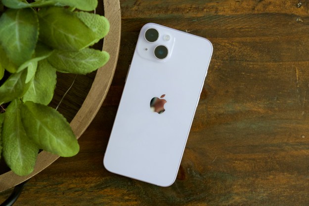 An iPhone 14 laying face-down on a wood table.