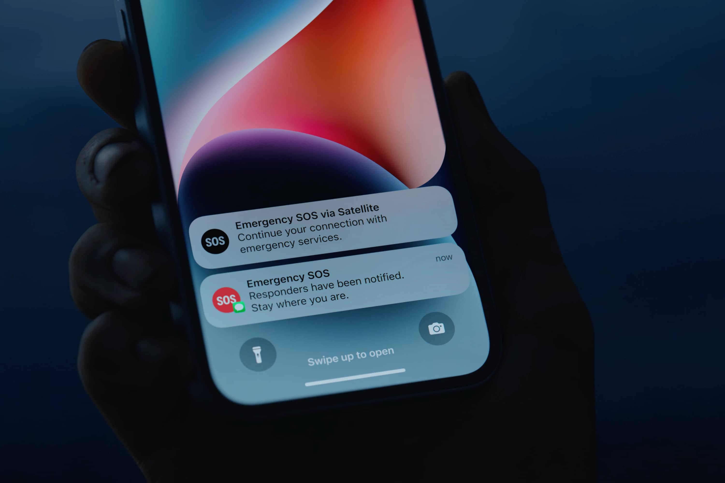 Personne tenant un iPhone 14 avec SOS d'urgence via des notifications par satellite.