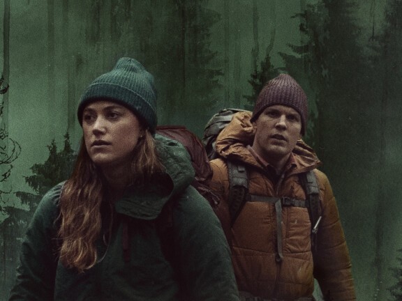 Maika Monroe und Jake Lacy wandern in einem Werbebild von Significant Other durch einen Wald.