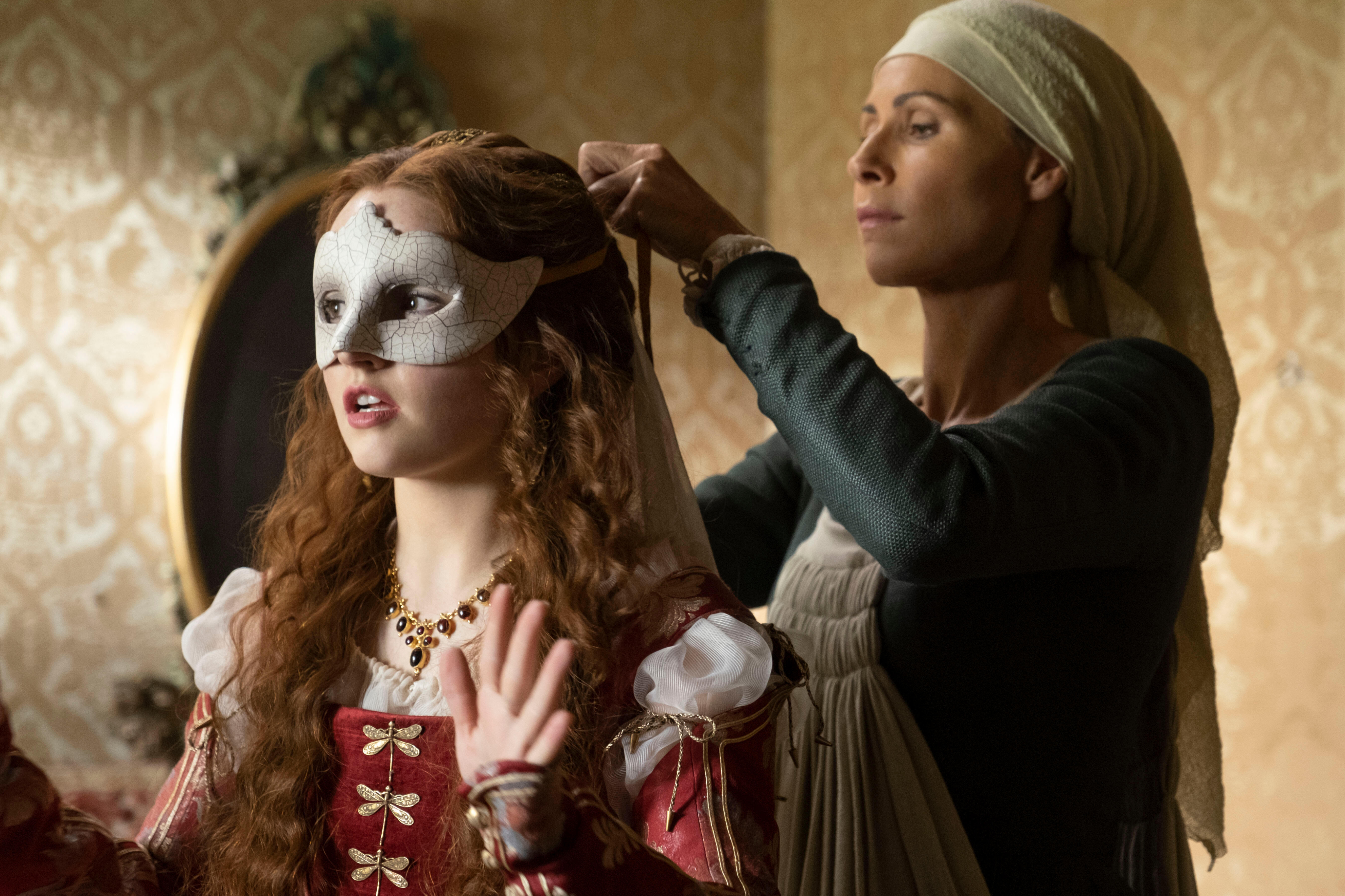 Minnie Driver le pone una máscara de baile a Kaitlyn Dever en Rosaline de Hulu.