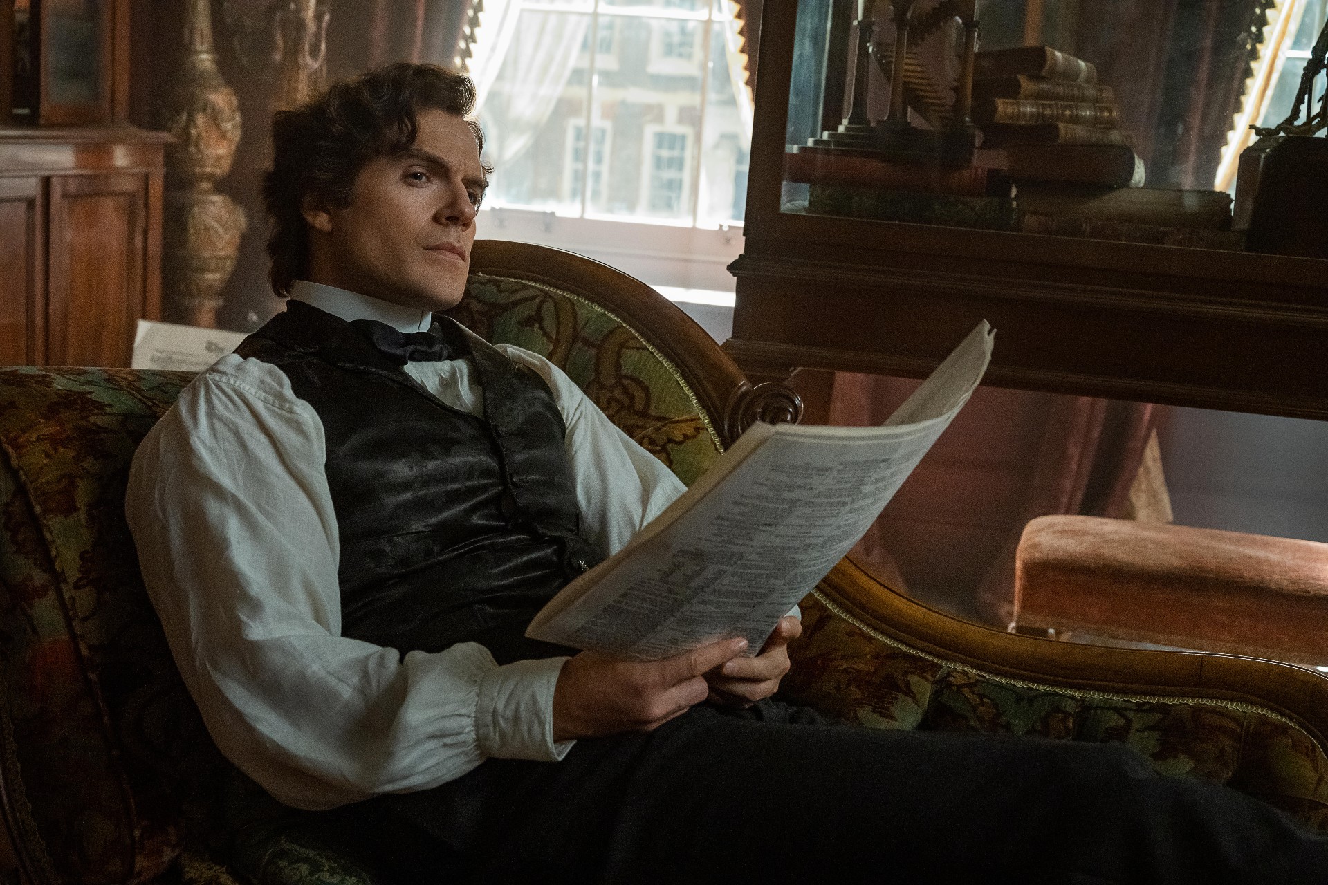 Henry Cavill reclines as Sherlock Holmes in a scene from Enola Holmes 2.