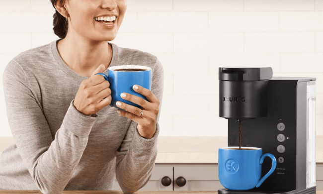 A woman sitting next to a Keurig K-Express coffee maker.