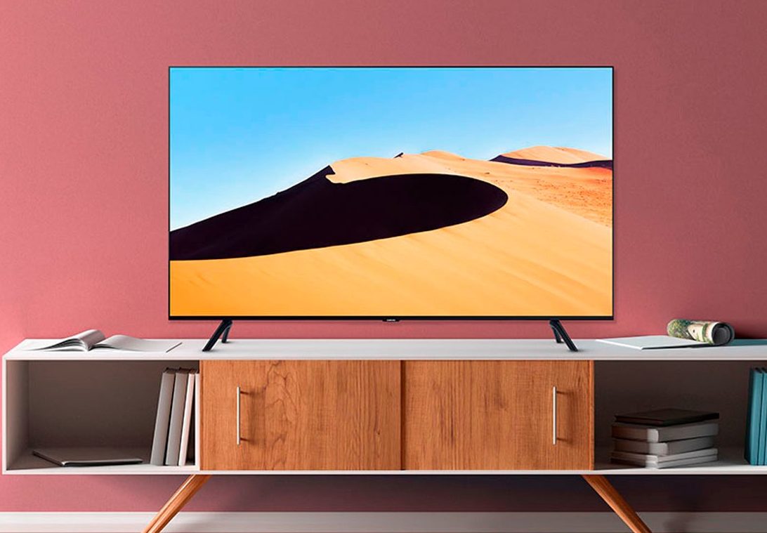 A Smart TV Samsung TU69OT 4K em um gabinete de mídia em uma sala de estar.