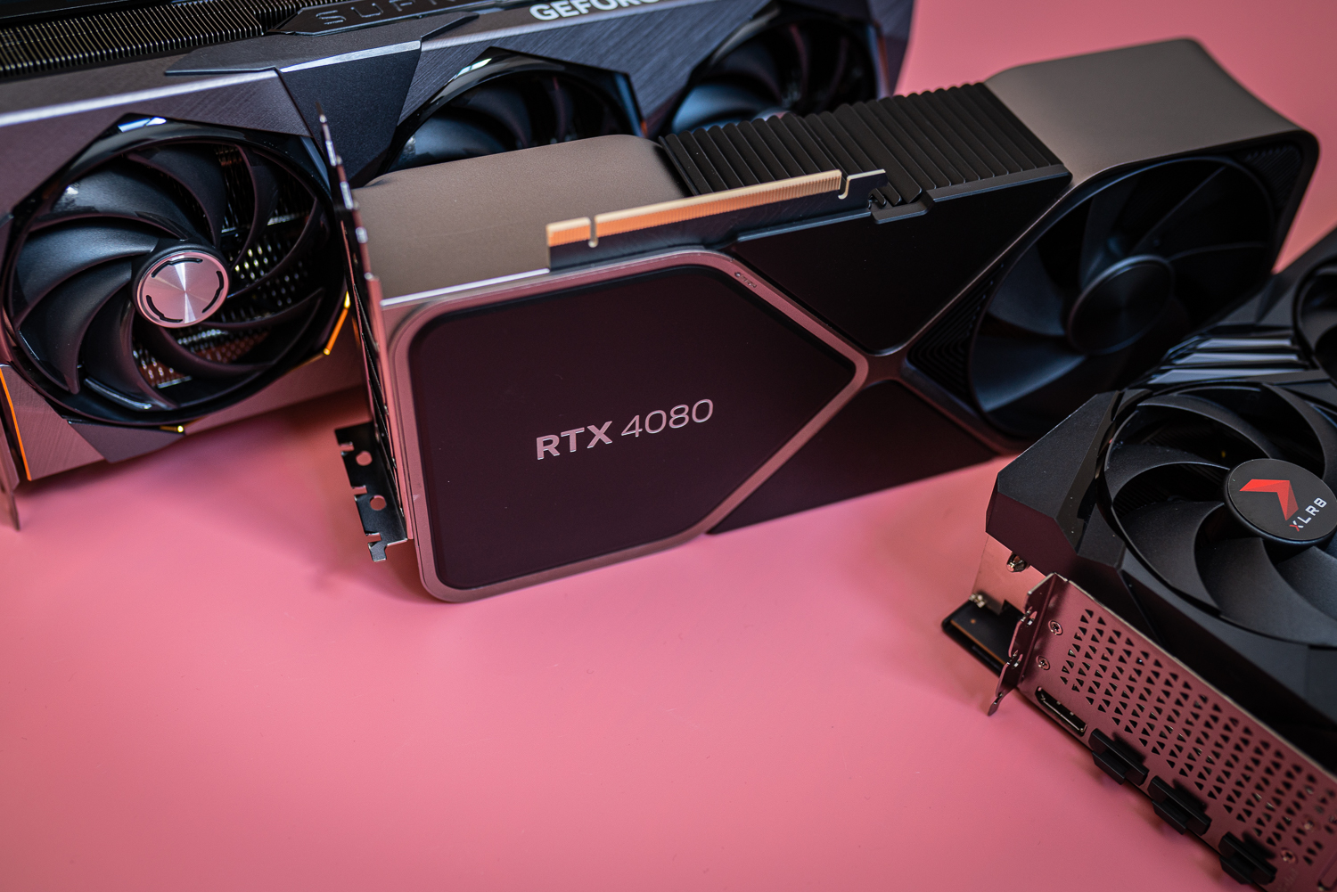 Drei RTX 4080-Karten sitzen auf einem rosa Hintergrund.