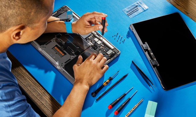 A person repairing a MacBook using Apple's self-service repair kit.