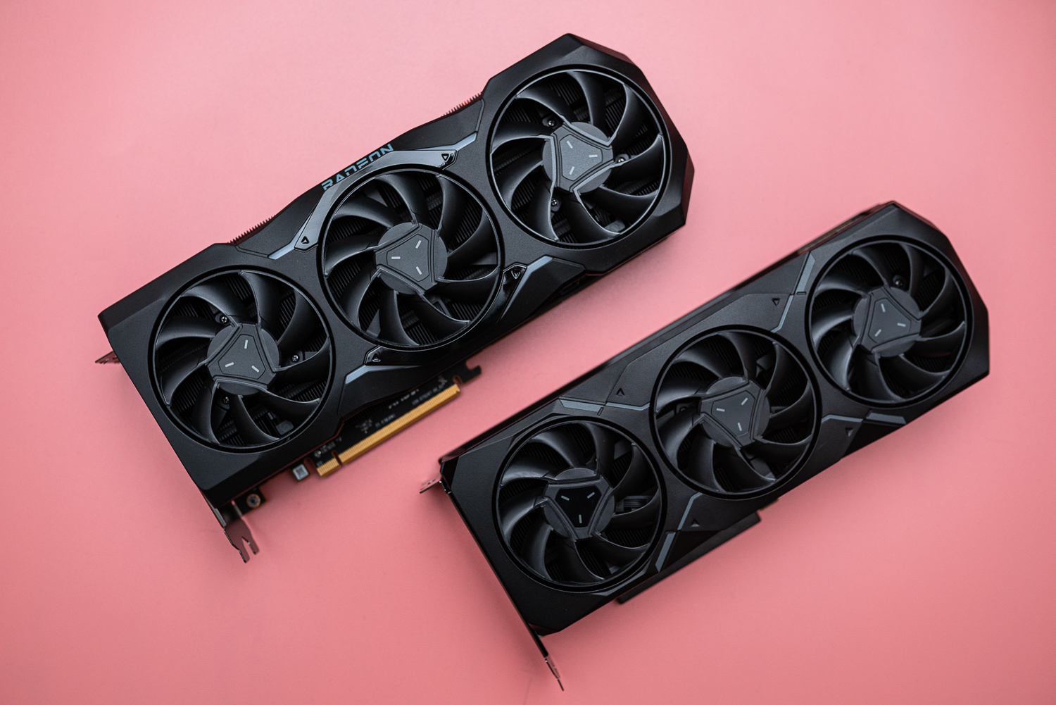 Zwei AMD Radeon RX 7000 Grafikkarten auf einer rosafarbenen Fläche.