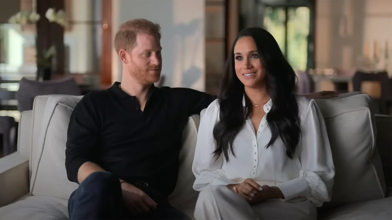 Harry e Meghan sentados em um sofá durante uma entrevista para Harry & Meghan.