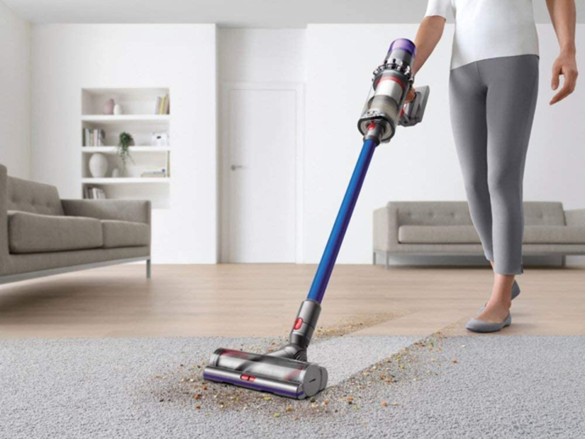 Dyson V11 Torque Drive cordless vacuum cleaner cleaning a messy living room carpet.