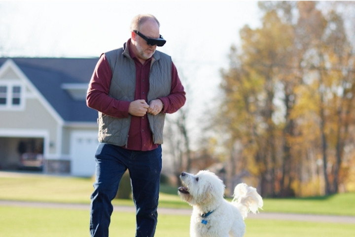 Man wearing eSight Go, walking with a dog.