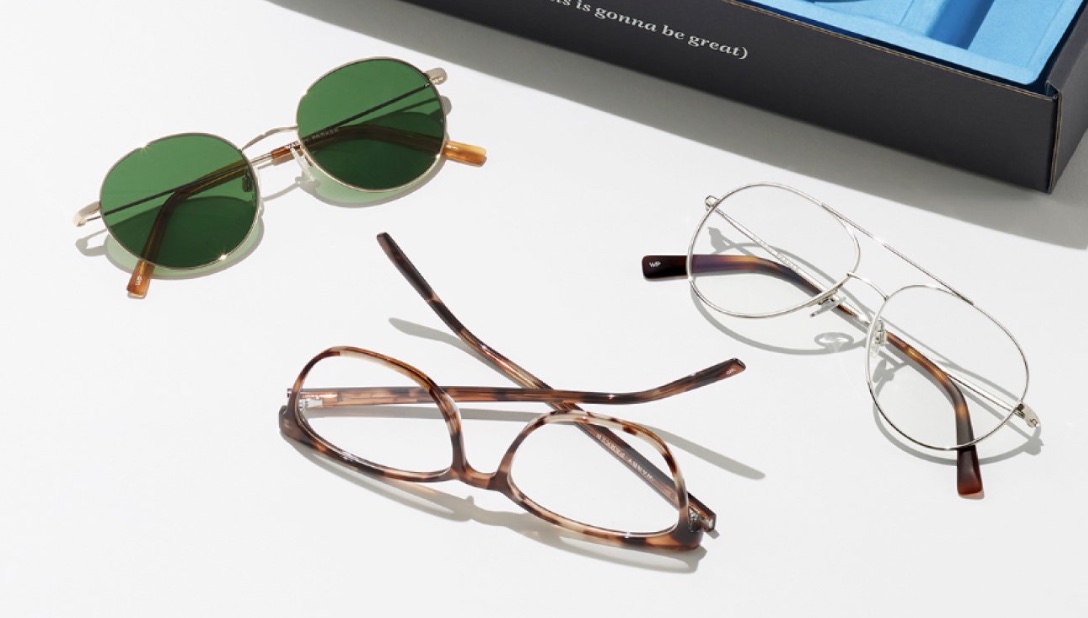 Three pairs of glasses next to a box on a white background.