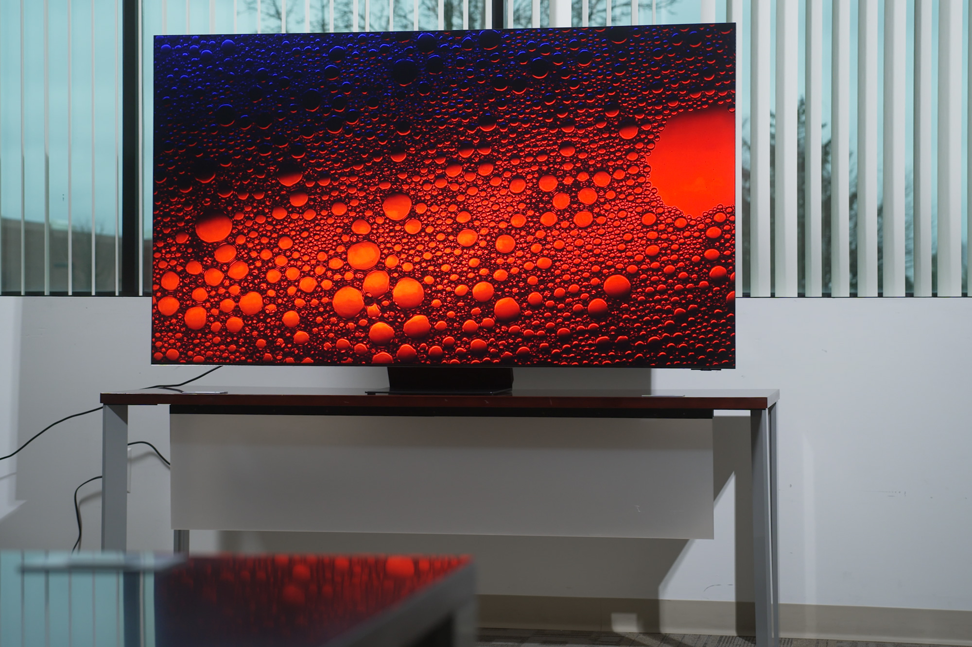 The Samsung QN900C QLED 8K Smart Tizen TV on a stand in a living room.