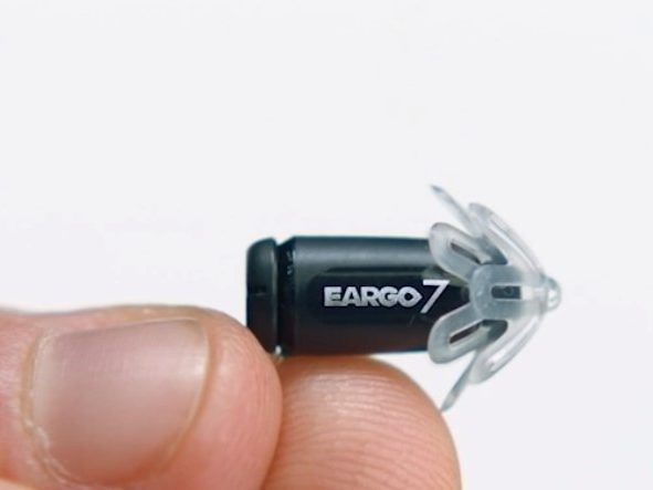 The tiny Eargo 7 OTC hearing aid with fingertips for scale.